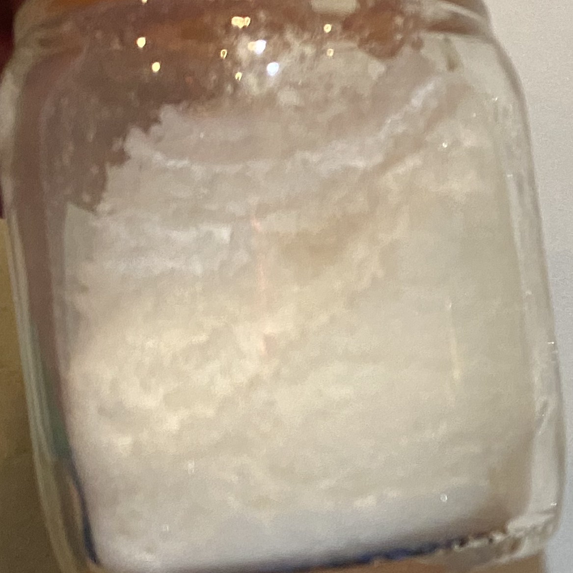 Small glass jar filled with clumpy white power